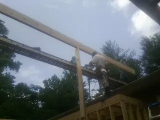 Carpenter setting a ridge beam over a new addition frame — Ice Dam Removal by Roofing Brothers in Gateway