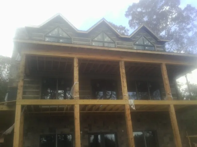 Dormers and porch framing on a large log home under construction — Roof Coating work by our crew in Gateway