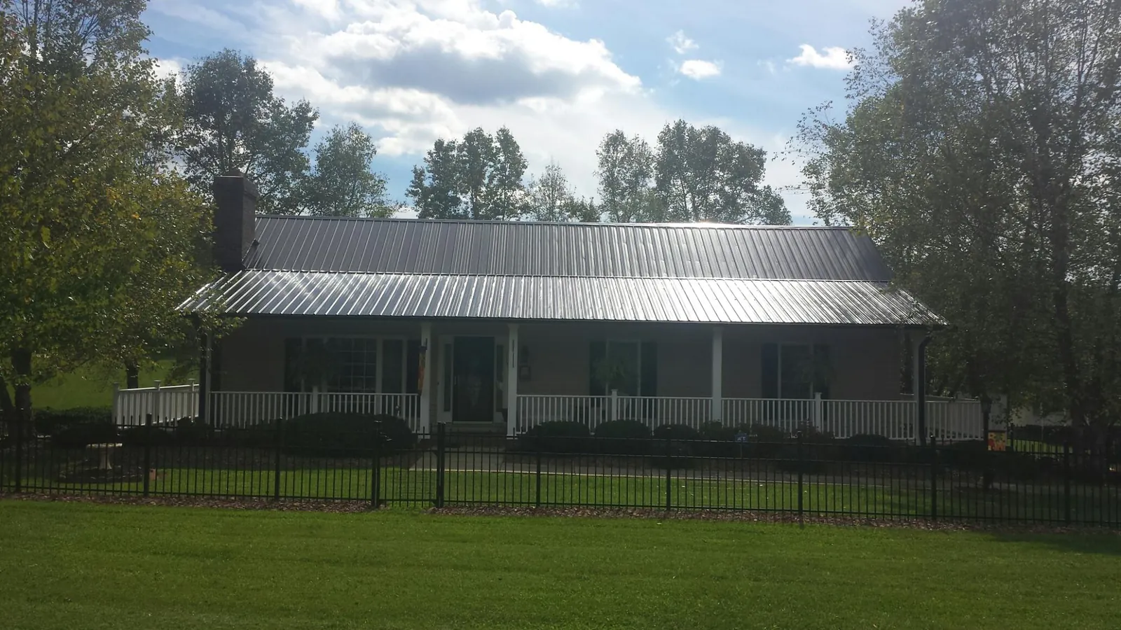 Gray metal roof on a brick ranch with a full width front porch — Gutter Guard Installation work by our crew in Gateway