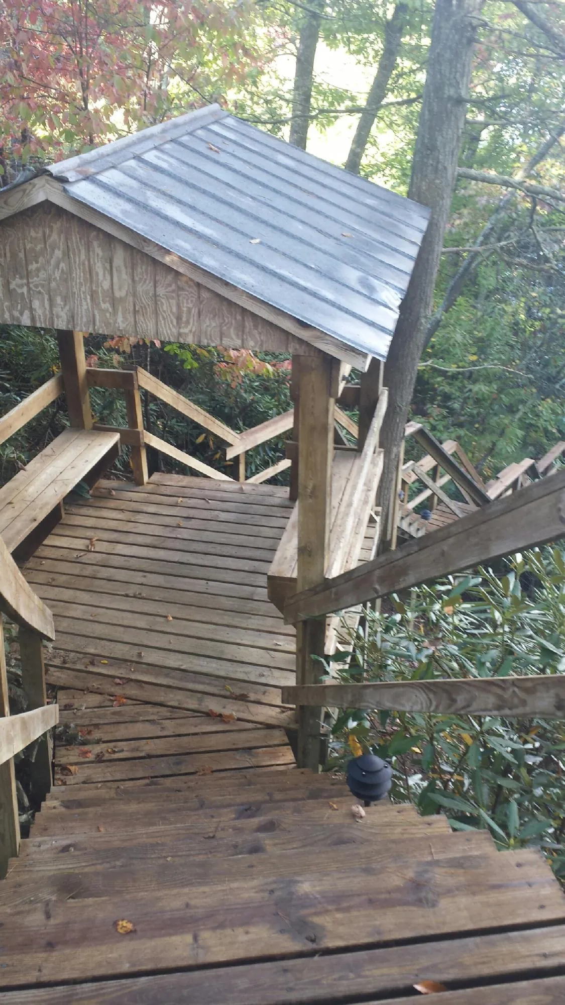 Metal roofed shelter over wooden steps on a wooded walkway — Skylight Repair & Installation work by our crew in Gateway