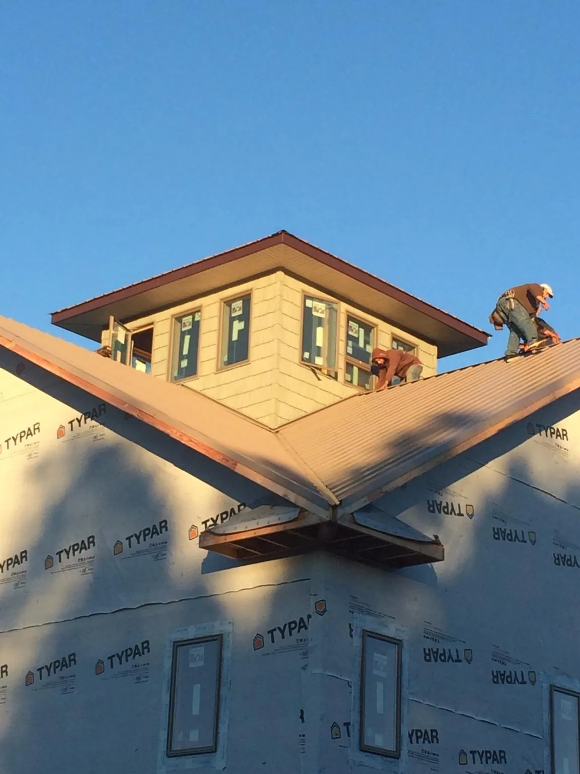 Roofers working around a rooftop cupola on a new metal roof at sunset — Roof Waterproofing in Gateway by Roofing Brothers